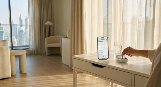 A clean, sunlit modern apartment desk with a discreet at-home medical testing kit, smartphone, and glass of water in warm morning light.